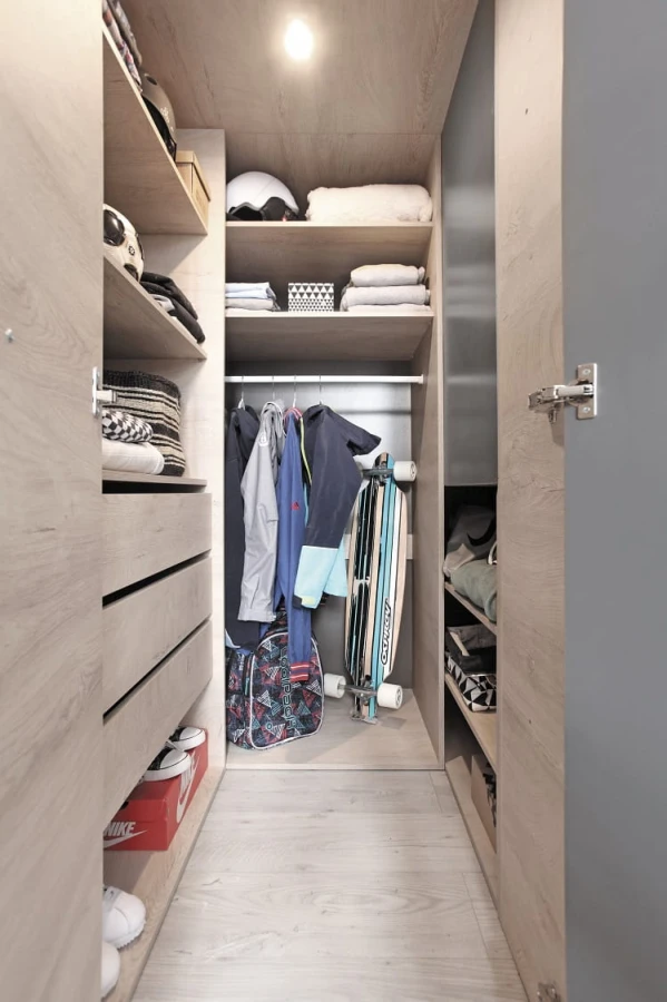 Gut organisierter begehbarer Kleiderschrank in heller Holzoptik mit vielen Regalfächern.
