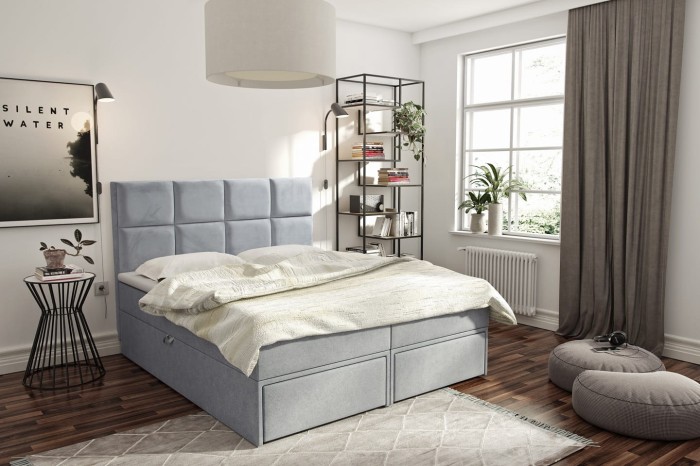 Hellblaues Boxspringbett mit modernem Kopfteil in hellem Interieur.