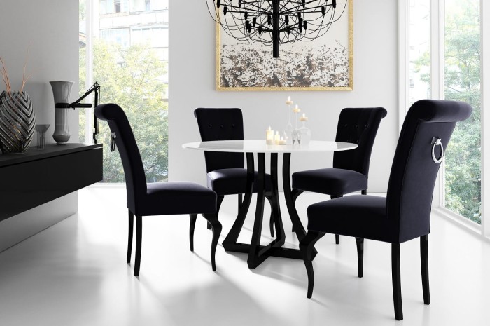 Essgruppe mit vier schwarzen Samtstühlen und einem runden weißen Design-Esstisch.