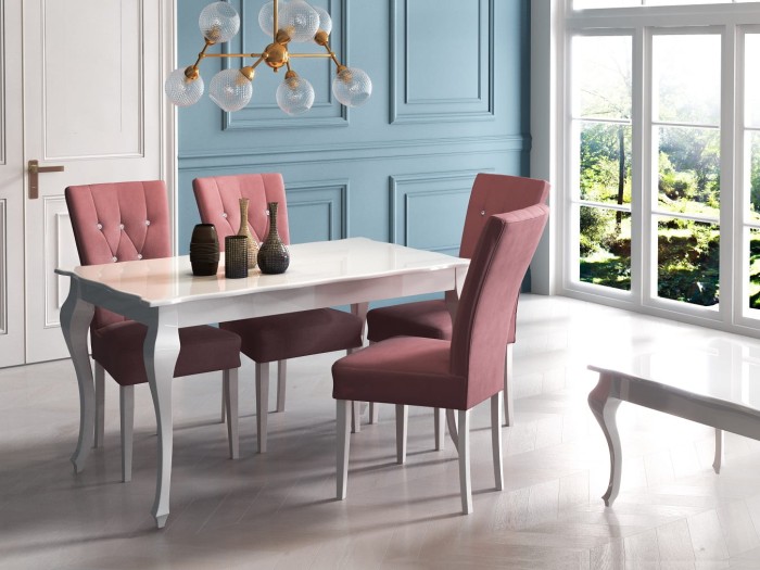 Stilvolles Esszimmer-Set: Weißer Tisch mit vier rosa Samtstühlen vor einer blauen Wand.