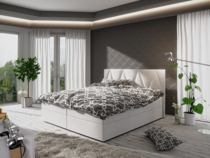 Modernes weißes Boxspringbett mit grau gemusterter Bettwäsche im hellen Schlafzimmer.