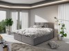 Hellgraues Boxspringbett mit dekorativem Kopfteil und stilvoller Bettwäsche.
