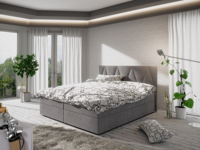 Hellgraues Boxspringbett mit dekorativem Kopfteil und stilvoller Bettwäsche.