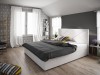 Weißes Polsterbett mit Rautensteppung am Kopfteil und grauer Bettwäsche im modernen Schlafzimmer.