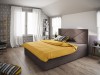 Braunes Doppelbett mit gelber Decke und elegant gestepptem Kopfteil.