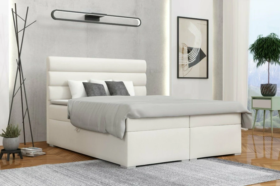 Weißes Boxspringbett im modernen Schlafzimmer mit stilvoller Dekoration und Teppich.