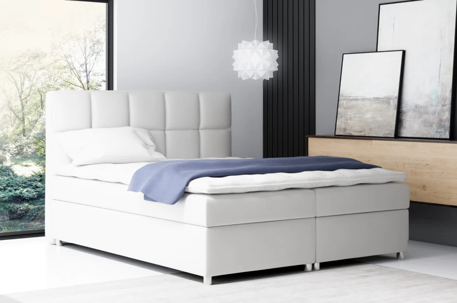 Modernes weißes Boxspringbett mit gestepptem Kopfteil im Schlafzimmer.