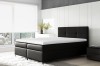 Modernes schwarzes Boxspringbett mit gepolstertem Kopfteil und weißem Topper im hellen Zimmer.
