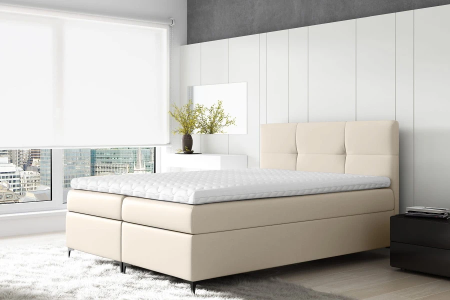 Elegantes beiges Boxspringbett in modernem Schlafzimmer mit weißer Matratzenauflage.