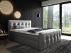 Modernes Boxspringbett in Hellgrau mit Quadratsteppung in dunklem Schlafzimmer mit Waldblick.