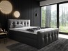 Anthrazitfarbenes Boxspringbett mit Steppmuster vor edler schwarzer Holzwand.