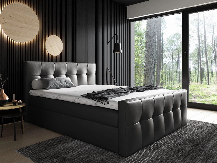 Anthrazitfarbenes Boxspringbett mit Steppmuster vor edler schwarzer Holzwand.
