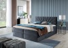 Graues Boxspringbett mit dekorativem Fächer-Kopfteil in einem hellen, modernen Zimmer.