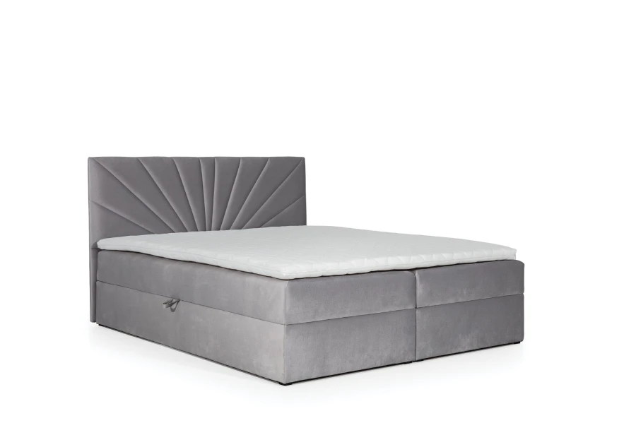Graues Boxspringbett mit markantem fächerförmigem Kopfteil und weißem Topper auf weißem Hintergrund.