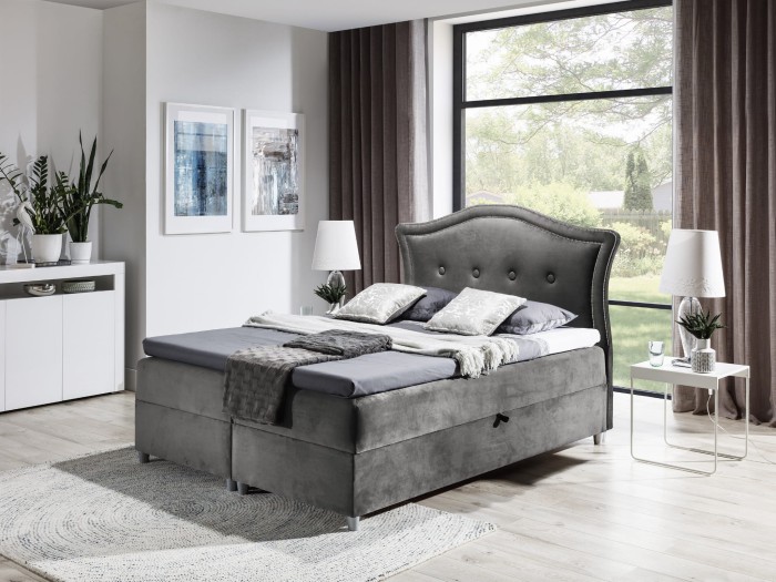 Graues Boxspringbett mit gestepptem Kopfteil und Stauraum in einem modernen Schlafzimmer.