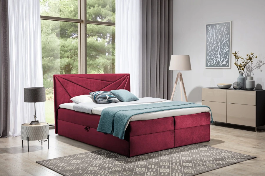 Elegantes weinrotes Boxspringbett mit Polsterkopfteil und Stauraum in gemütlichem Schlafzimmer.