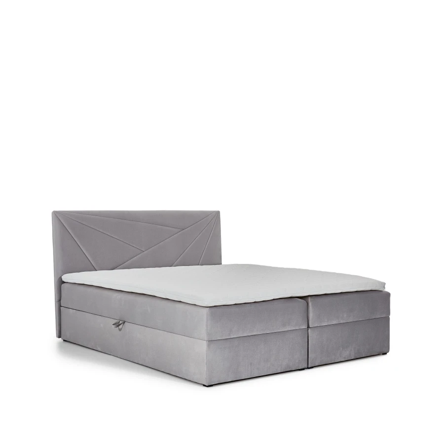 Hellgraues Boxspringbett mit Topper und dekorativem Kopfteil freigestellt auf weißem Hintergrund.