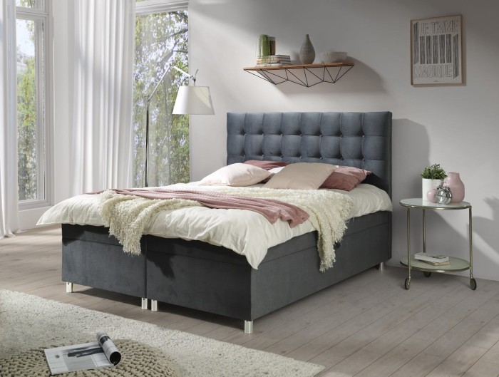 Boxspringbett in Dunkelgrau mit dekorativer Steppung am hohen Kopfteil.