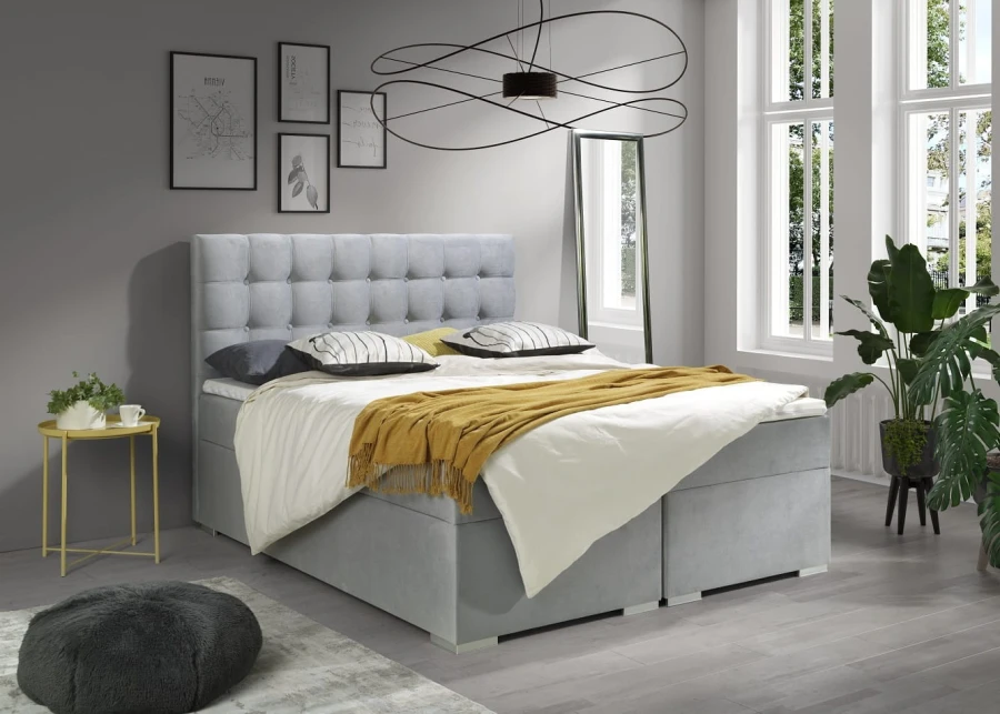 Hellgraues Boxspringbett mit Knopfsteppung am Kopfteil in hellem Schlafzimmer.