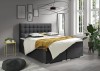 Anthrazitfarbenes Boxspringbett mit Polsterkopfteil und gemütlicher Bettwäsche.
