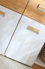 Nahaufnahme moderner Möbelgriffe in Eiche-Optik auf weißen Schranktüren.