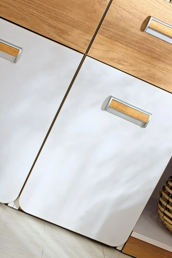 Nahaufnahme moderner Möbelgriffe in Eiche-Optik auf weißen Schranktüren.