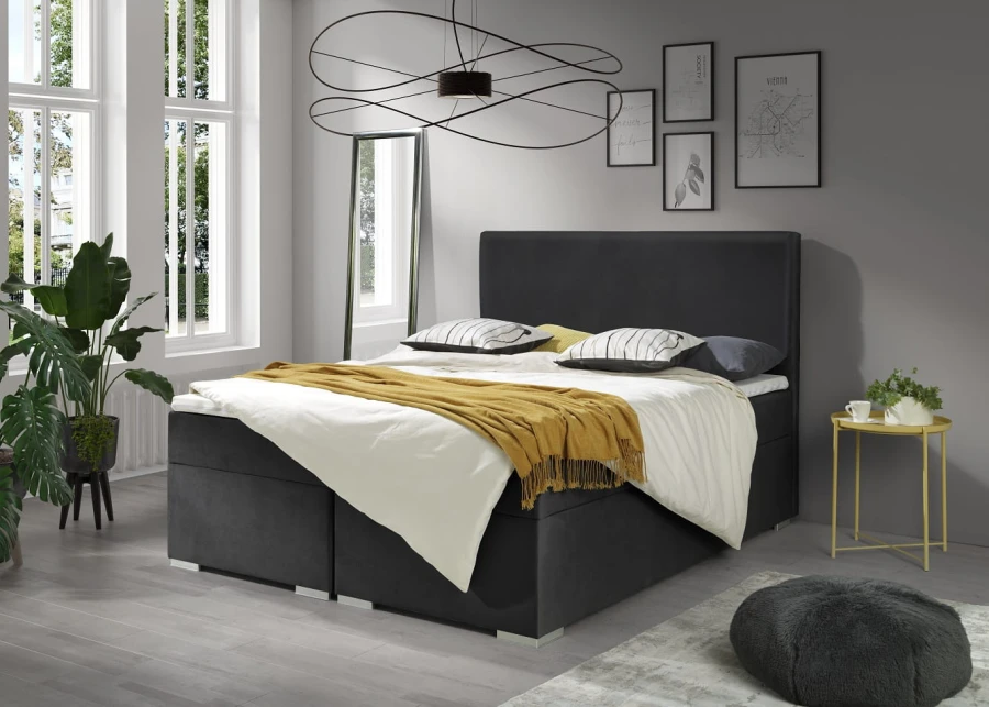 Anthrazitfarbenes Samt-Boxspringbett in einem stilvoll eingerichteten Schlafzimmer.