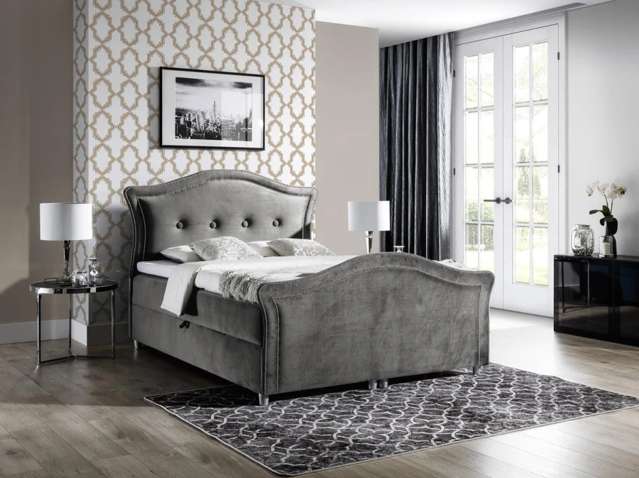 Modernes graues Samtbett mit geschwungenem Kopfteil und Ziernagel-Besatz.