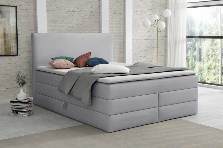 Komfortables hellgraues Boxspringbett im zeitlosen Design für gemütliche Nächte.