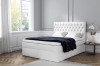 Modernes weißes Boxspringbett mit stilvoll gestepptem Kopfteil.