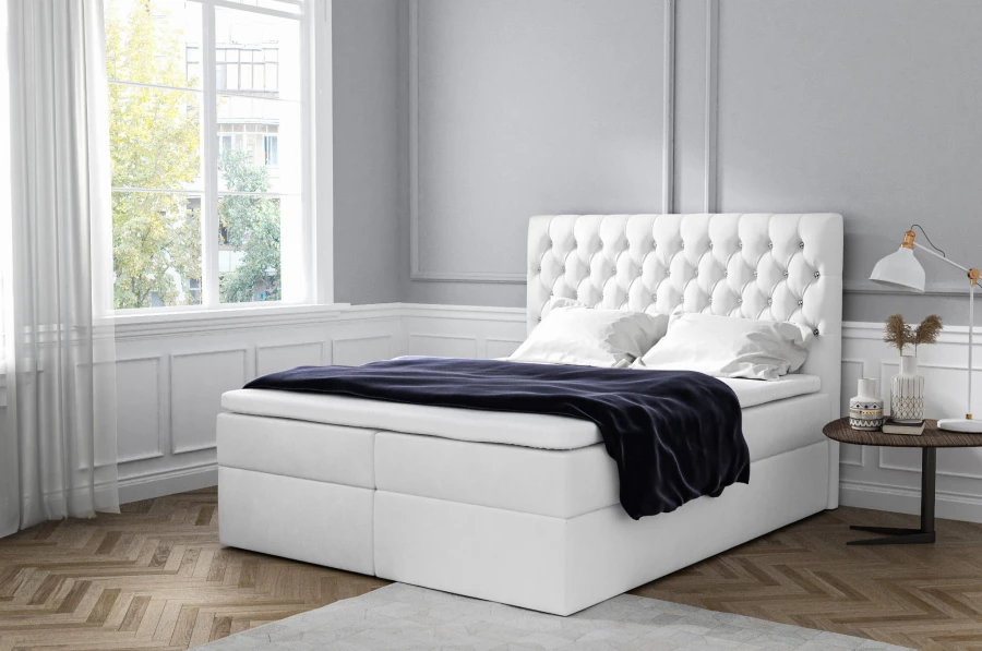 Modernes weißes Boxspringbett mit stilvoll gestepptem Kopfteil.