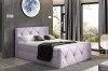 Fliederfarbenes Boxspringbett mit gepolstertem Kopfteil und moderner Wanddekoration im Zimmer.