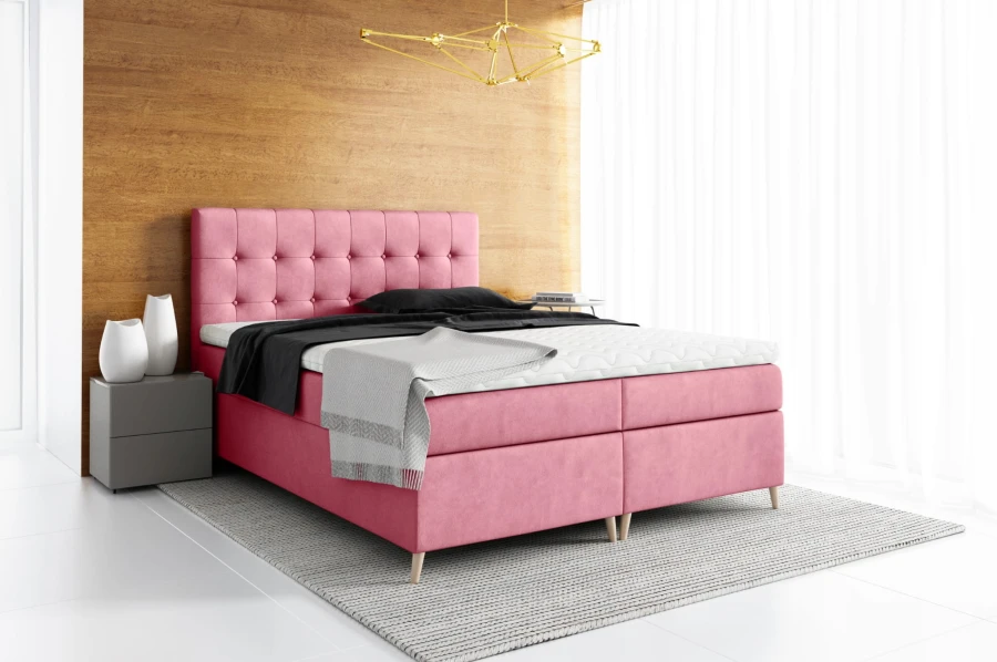 Rosa Boxspringbett mit gestepptem Kopfteil und hellen Holzfüßen in modernem Schlafzimmer.