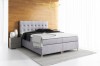 Hellgraues Boxspringbett mit eleganter Knopfheftung am Kopfteil für stilvolles Wohnen.