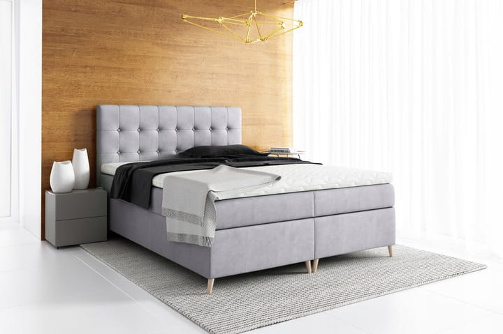 Hellgraues Boxspringbett mit eleganter Knopfheftung am Kopfteil für stilvolles Wohnen.