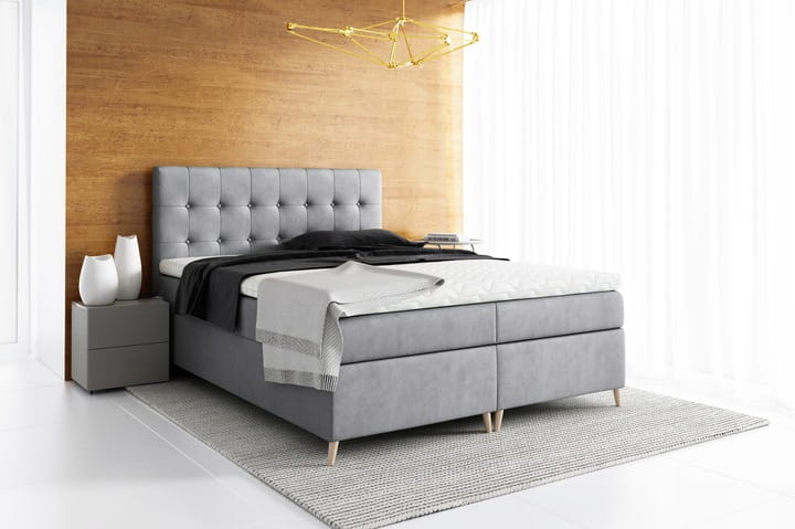 Modernes graues Polsterbett mit weicher Matratze und Topper in hellem Raum.