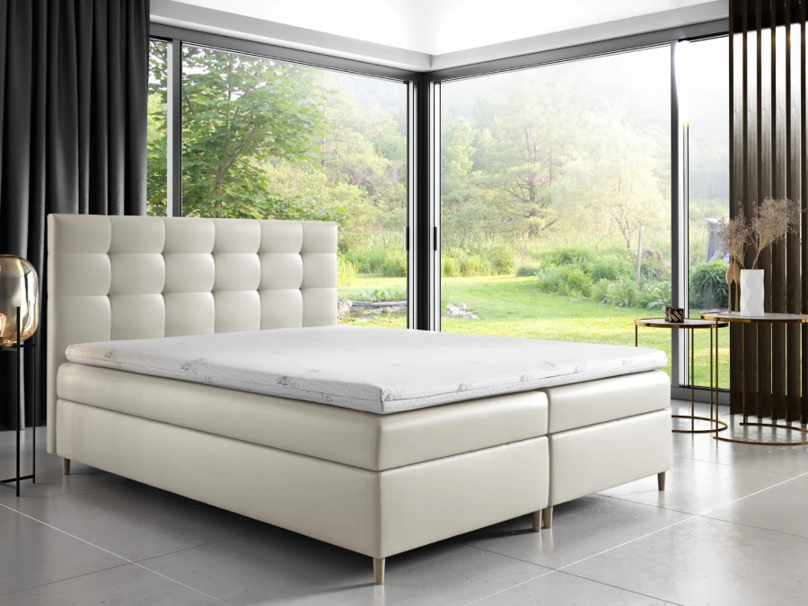 Modernes Boxspringbett in Beige mit gestepptem Kopfteil und Blick ins Grüne.