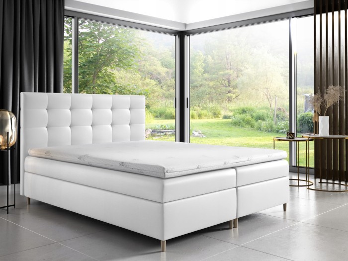 Elegantes weißes Boxspringbett in modernem Schlafzimmer mit großer Fensterfront.