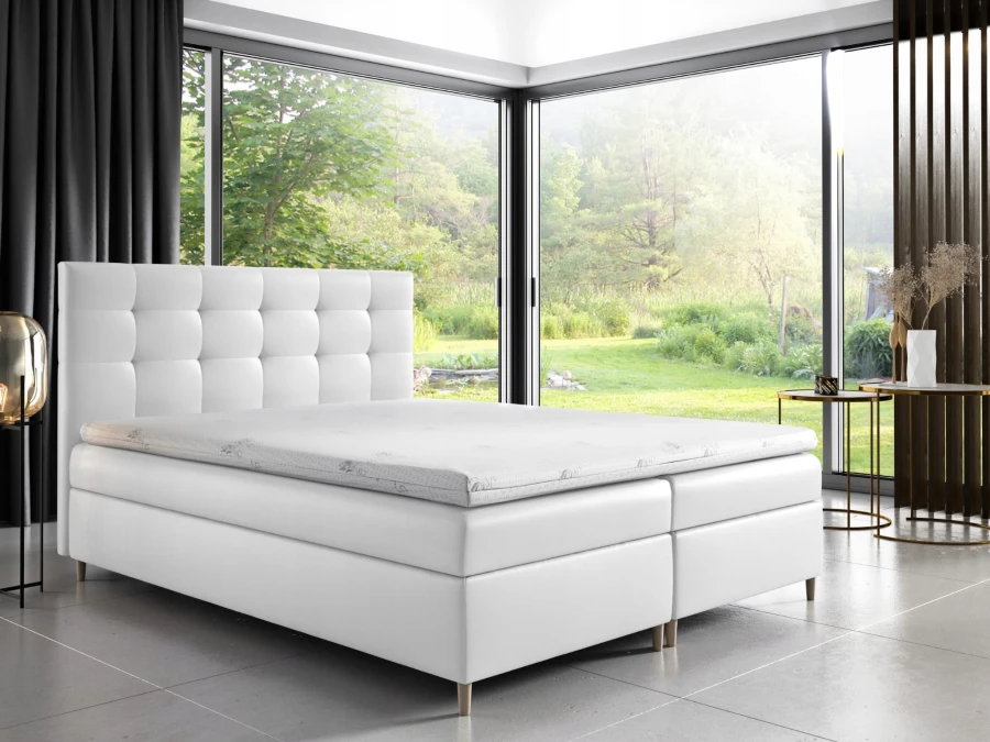 Elegantes weißes Boxspringbett in modernem Schlafzimmer mit großer Fensterfront.