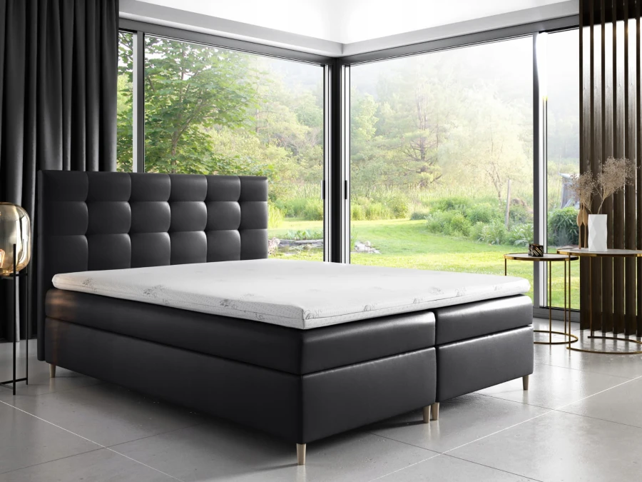 Schwarzes Boxspringbett aus Kunstleder im minimalistischen Schlafzimmer mit Waldblick.