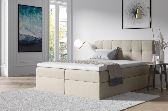 Elegantes beiges Boxspringbett mit gestepptem Kopfteil im Schlafzimmer.