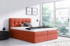 Modernes Boxspringbett in Terrakotta mit gepolstertem Kopfteil vor großem Fenster.