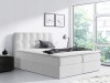 Elegantes weißes Boxspringbett mit hohem Kopfteil in modernem, lichtdurchflutetem Raum.