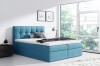 Blaues Boxspringbett mit gestepptem Kopfteil und gemütlichem Topper in hellem Schlafzimmer.