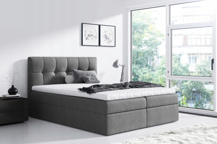 Modernes graues Boxspringbett im Schlafzimmer mit großem Fenster und schlichter Dekoration.