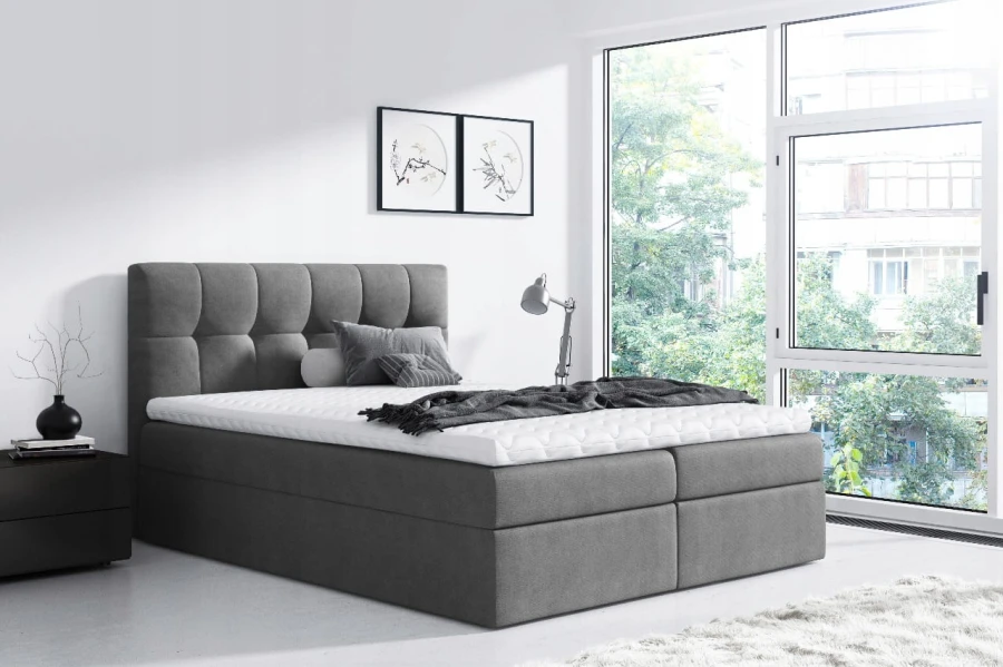 Modernes graues Boxspringbett im Schlafzimmer mit großem Fenster und schlichter Dekoration.
