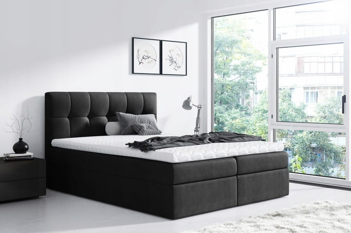 Schwarzes Boxspringbett mit Polster-Kopfteil und weißer Matratze in eleganter Einrichtung.