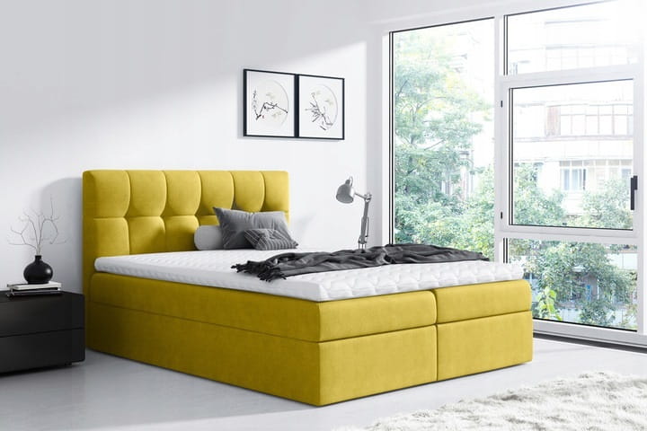 Modernes senfgelbes Boxspringbett mit gestepptem Kopfteil in hellem Schlafzimmer.