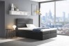 Anthrazitfarbenes Boxspringbett in modernem Schlafzimmer mit Ausblick auf die Stadt.