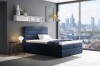 Dunkelblaues Boxspringbett in modernem Zimmer mit Panorama-Stadtblick und Design-Lampe.
